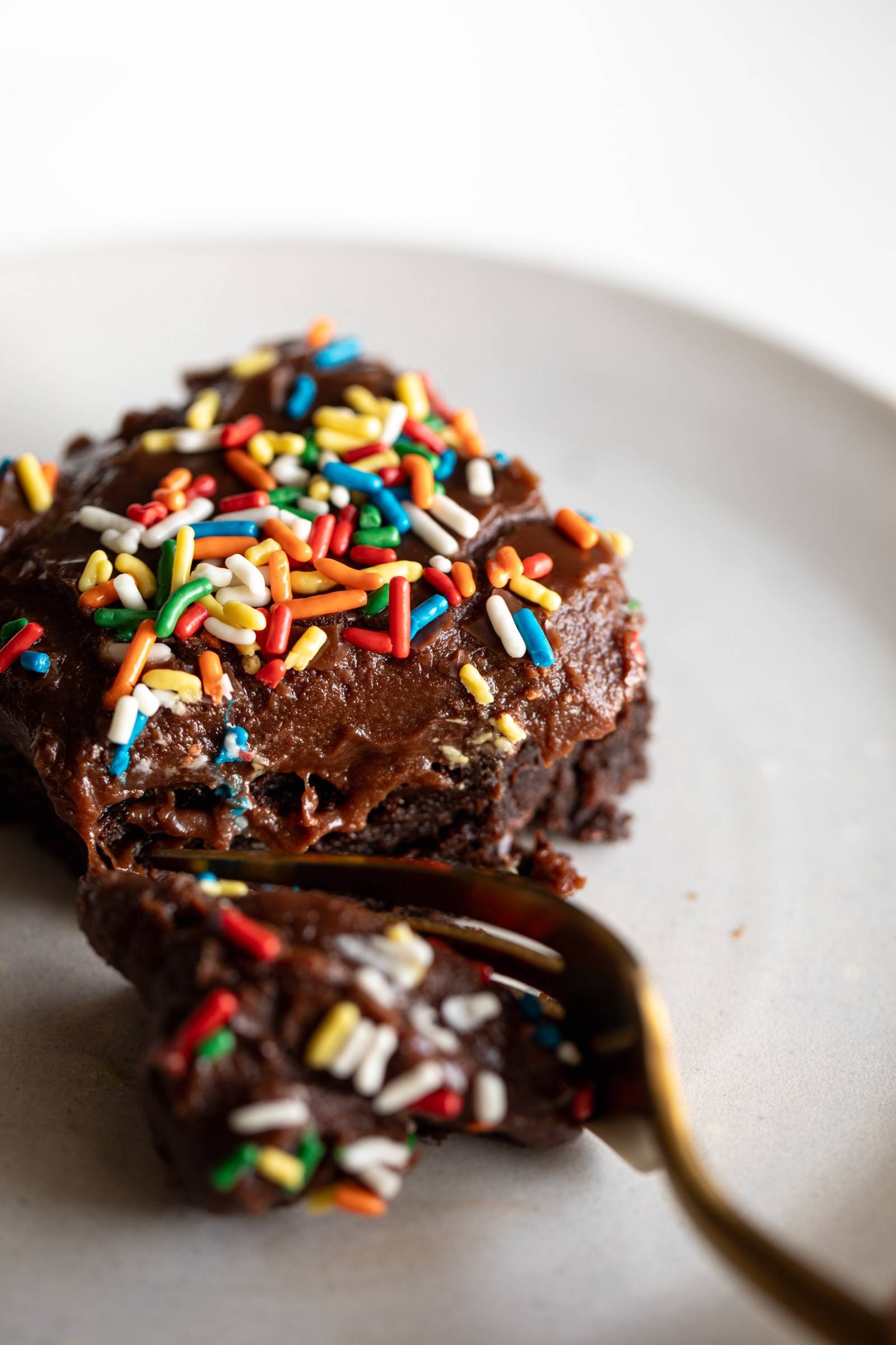 Fork taking a bit out of a brownie with sprinkles on it.